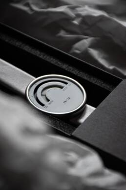 A sleek modern wristwatch, featuring a minimalist black and white arc design, rests in an elegant black box. The setting is sophisticated and stylish.